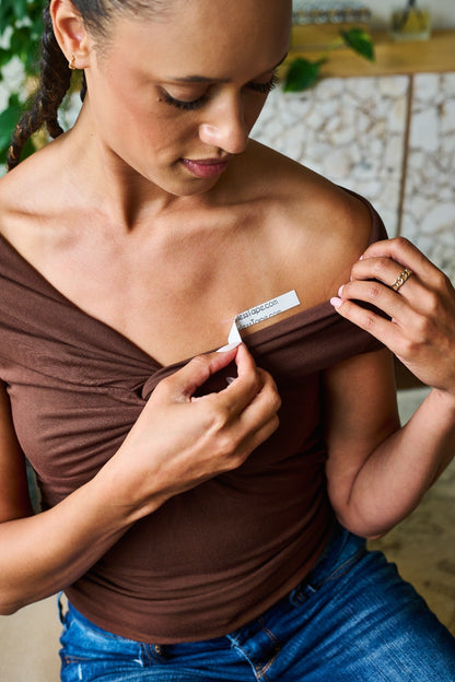 Picture of girl securing off the shoulder shirt in place with double sided tape