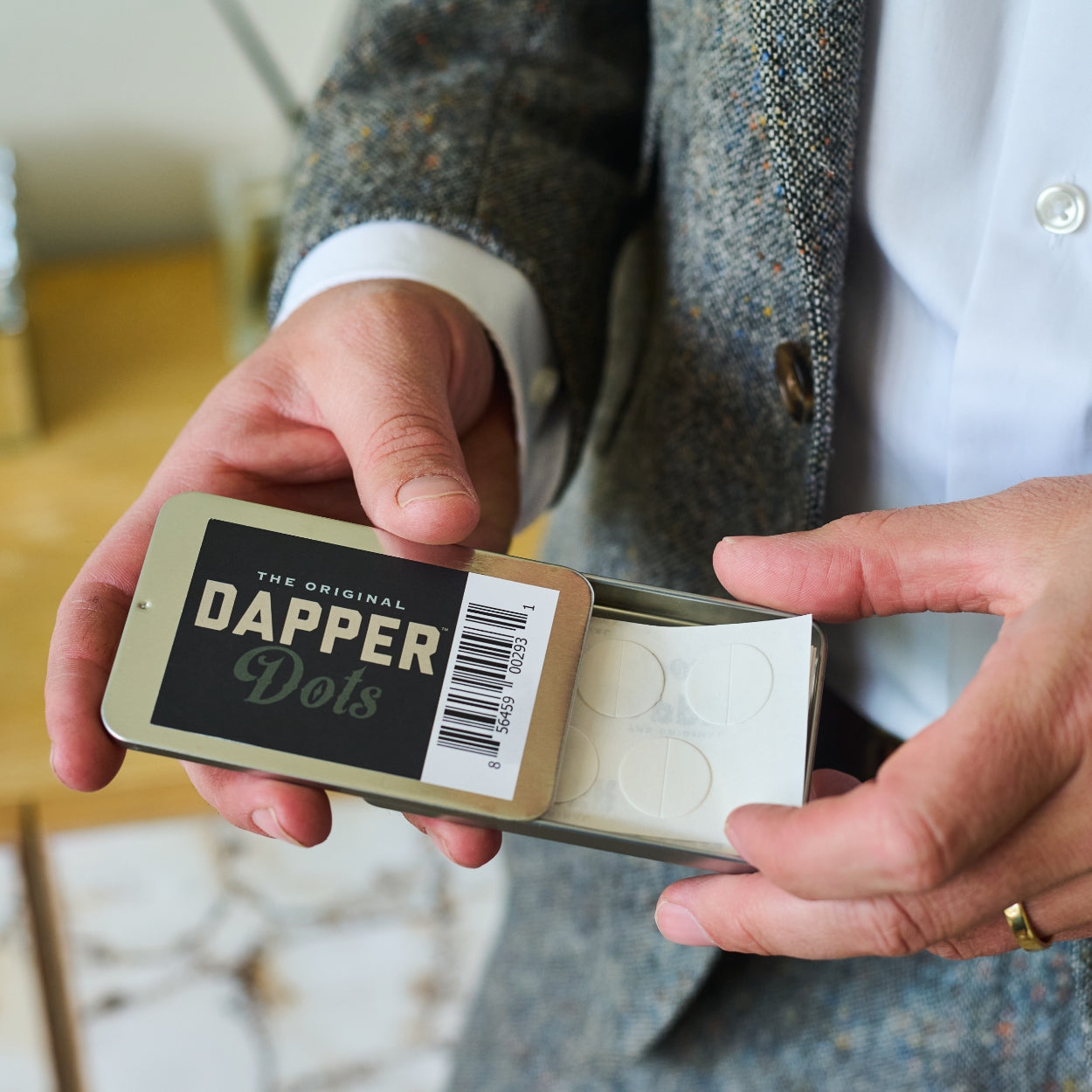 Person holding a small box labeled 'Dapper Dots' with a blurred background